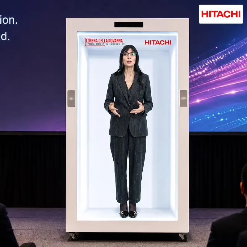 Lorena Dellagiovanna, Senior Vice President and Executive Officer at Hitachi, Ltd., appearing as a live full-height hologram on a HoloBox911 stage unit in New Delhi, with her on-screen name plate visible